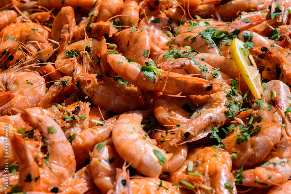 Close up of large portion of cooked shrimps with tomato sauce and green parsley in a large pan at a street food festival, ready to eat healthy seafood, beautiful orange monochrome outdoor background. Close up of large portion of cooked shrimps with tomato sauce and green parsley in a large pan at a street food festival, ready to eat healthy seafood, beautiful orange monochrome outdoor background.