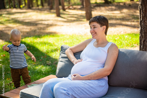 Happy pregnant woman sitting in summer Park © irena_geo