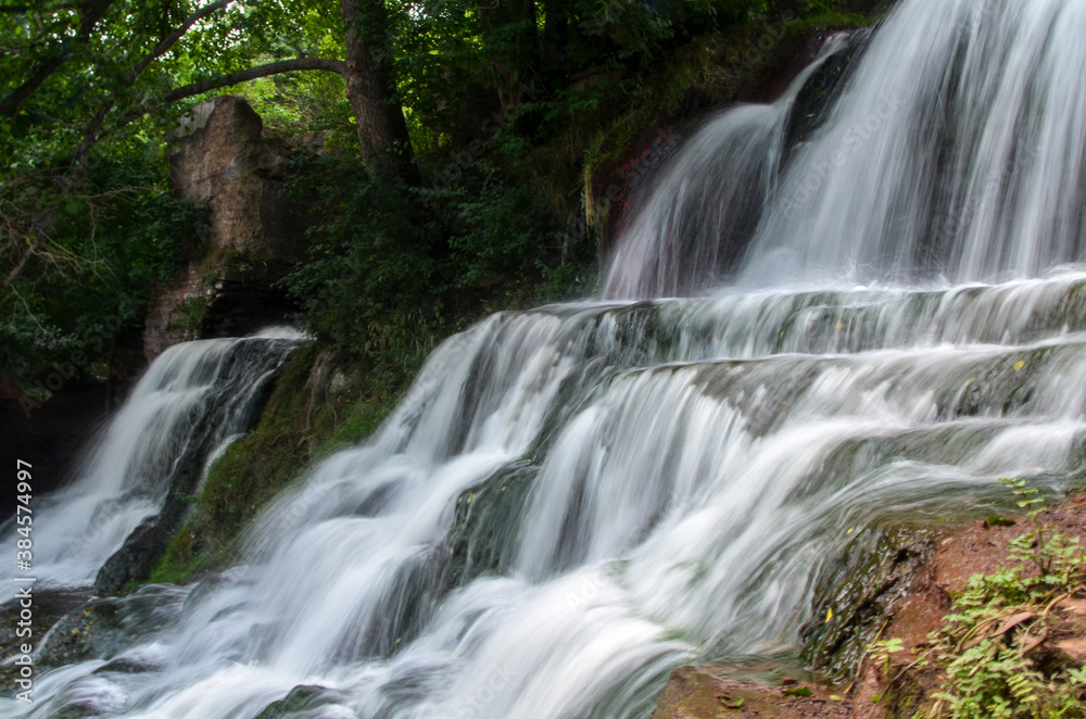 Scenic view of cascading 16 meters Dzhurinsky waterfall on the river Dzhurin. It is the largest in Ukraine plain waterfall. Nyrkiv, Ternopil region, Ukraine