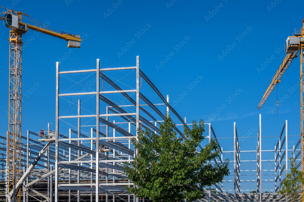 Bau eines großen Parkhauses mit Stahlbauweise vor blauem Himmel mit Baukränen