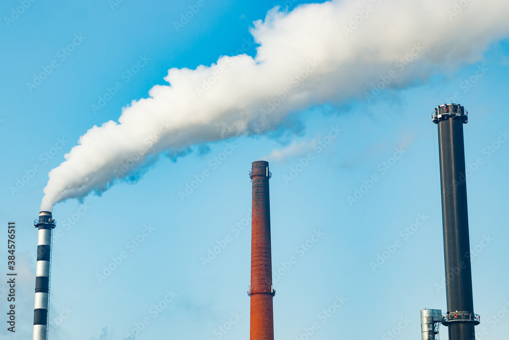 Chimney smoke at factory against blue sky