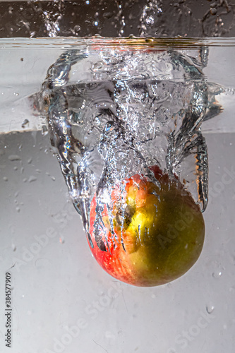 bubbles and splash after impact of an apple falling into water
