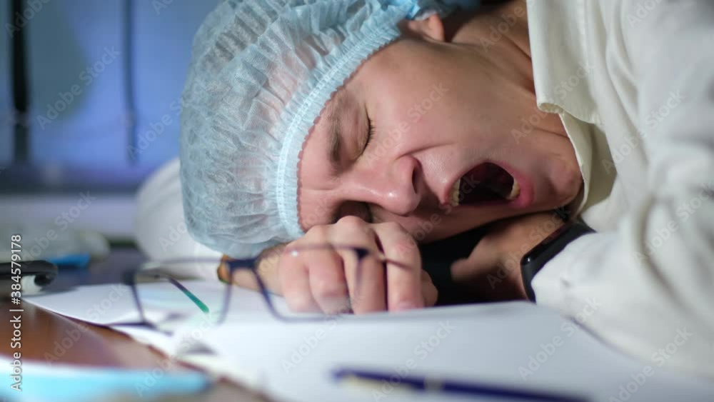 Tired and yawning doctor or scientist falling asleep at work place late at night. Concept of increased burden on medicine during the covid coronavirus pandemic Tired and yawning doctor or scientist falling asleep at work place late at night. Concept of increased burden on medicine during the covid coronavirus pandemic