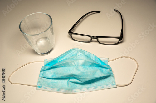 Surgical blue mask, glasses and an empty glass