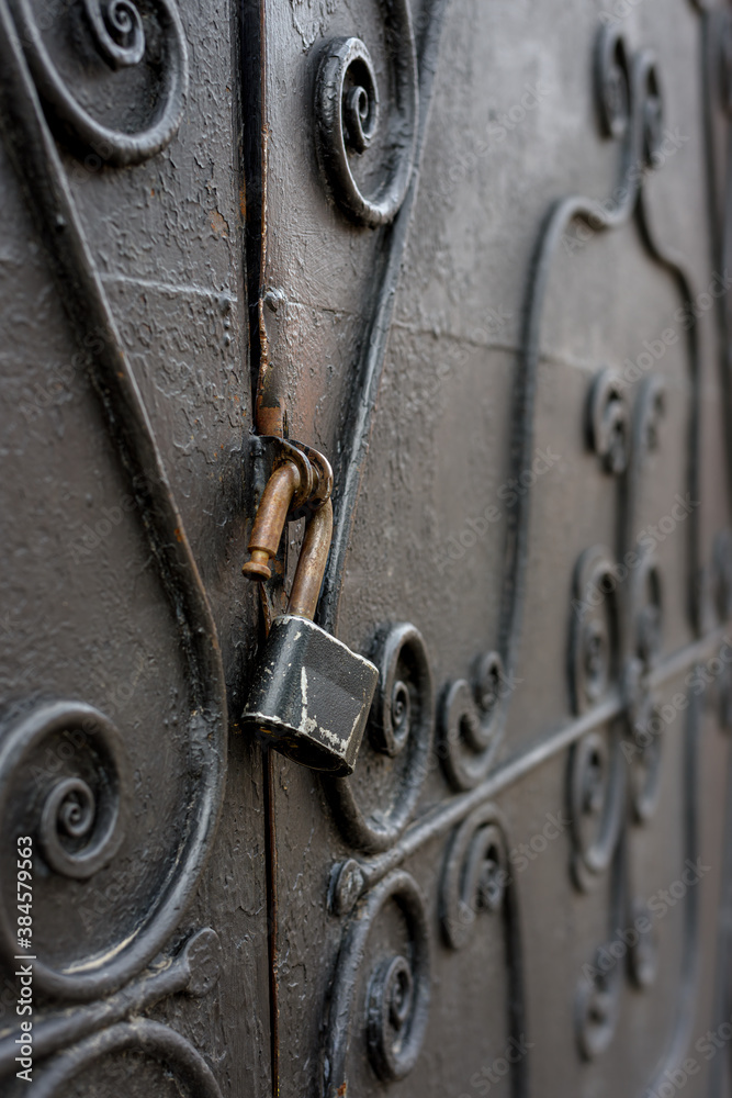 An open padlock hangs from a black iron gate. Focus on the lock An open padlock hangs from a black iron gate. Focus on the lock
