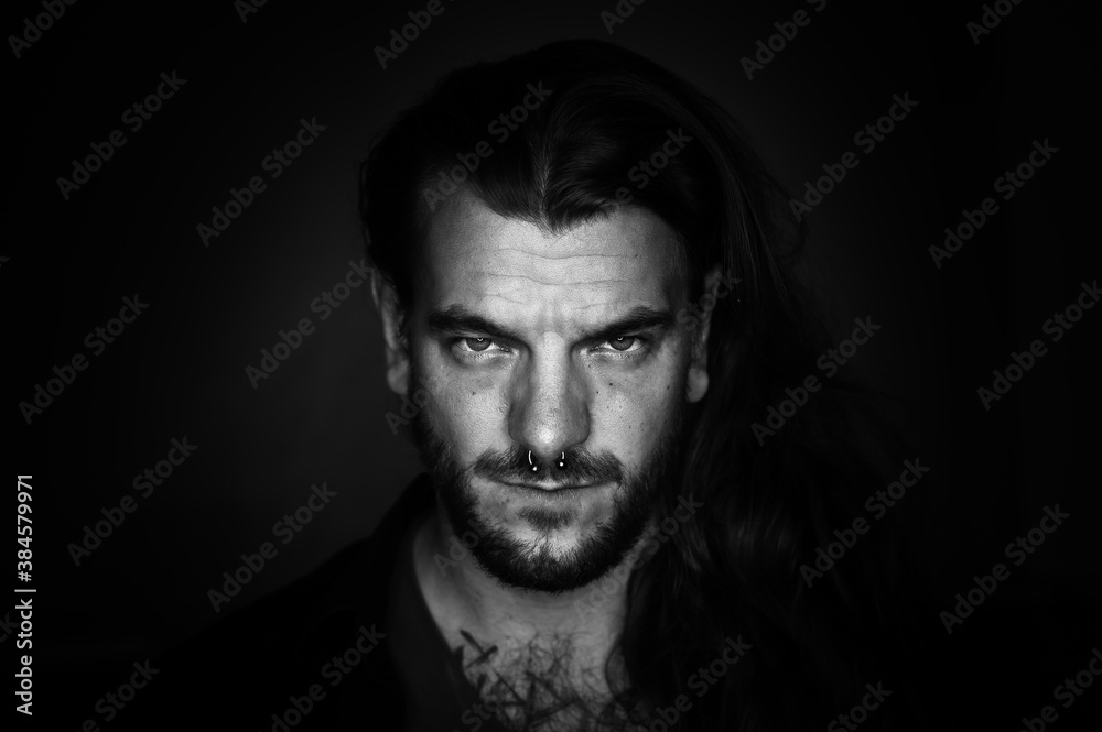 Man with long hair looks seriously and determined at the camera on an black and white image