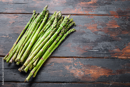 Raw organic asparagus on dark wooden old background, side view with space for text.
