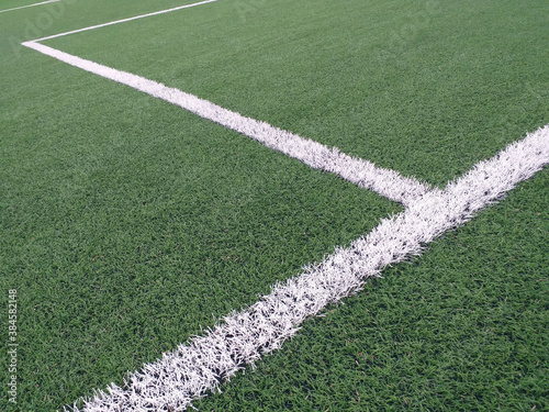 Sports lines painted on a green grass pitch. White lines painted on artificial grass on a soccer field View of artificial grass on a soccer field with lines painted white.