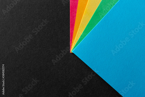 Colored rainbow paper corners on black textured background. Business concept. Layout for design. Copy space. High quality photo