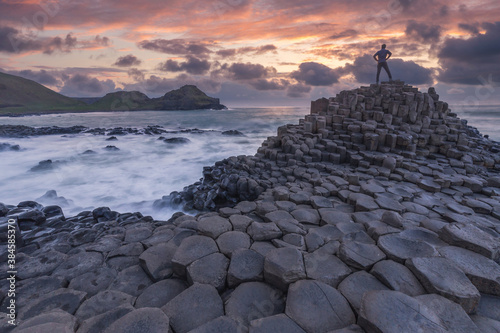 Silhouette of one person standing at Giant Causeway rocks at sunset in Northern Ireland 