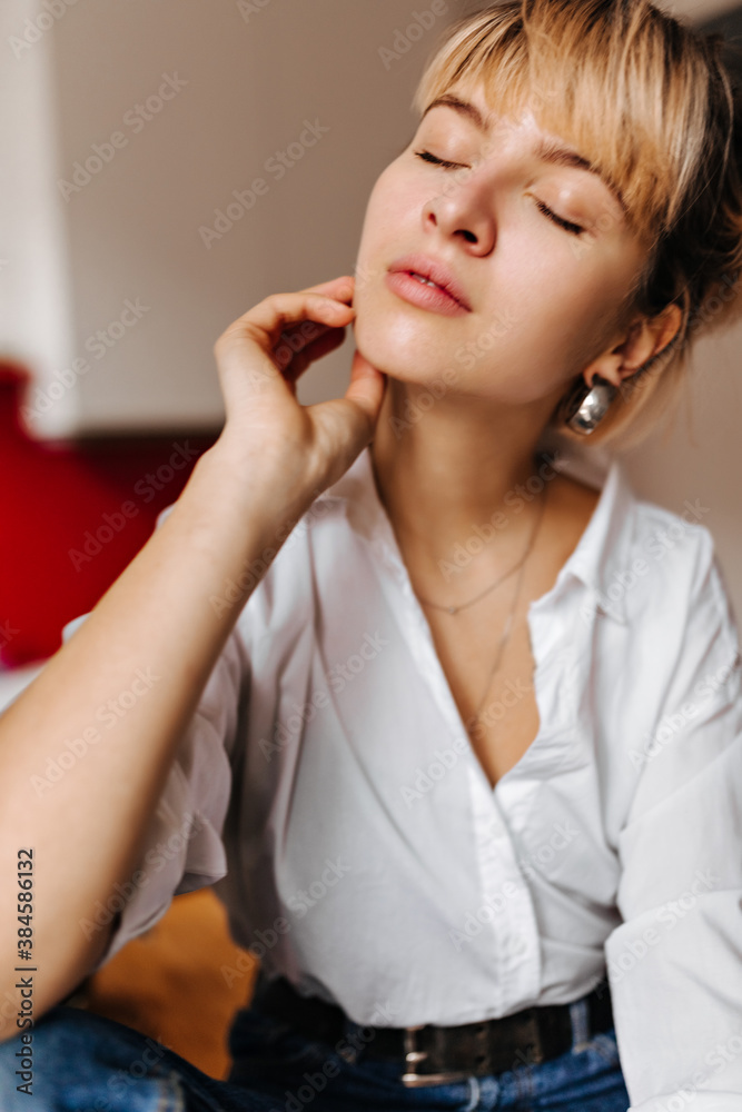 Adorable woman in earrings posing at home. Indoor shot of refined blonde girl with closed eyes. Adorable woman in earrings posing at home. Indoor shot of refined blonde girl with closed eyes.