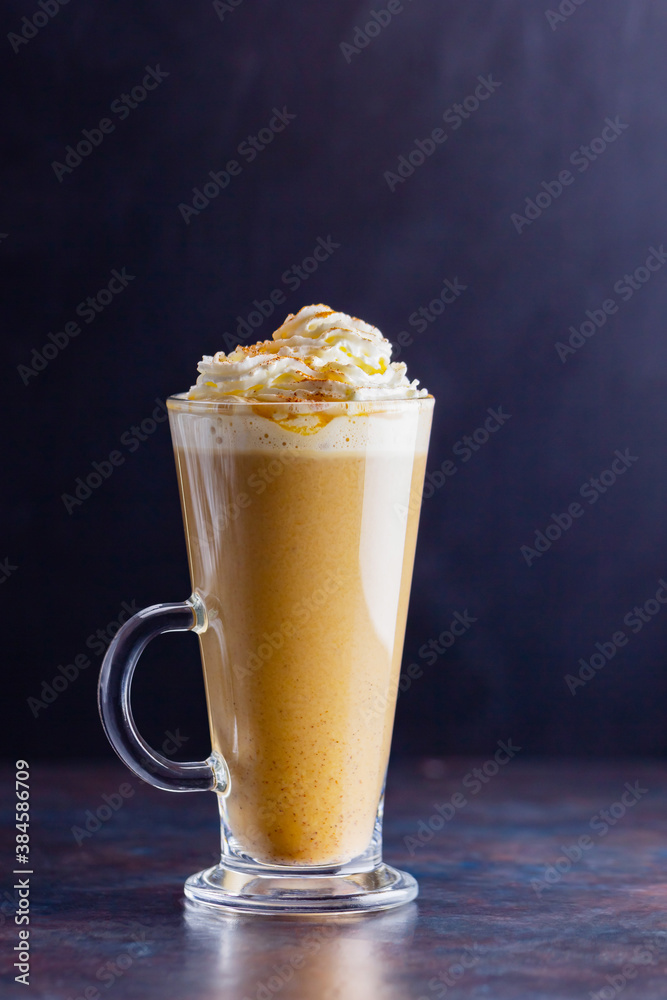 Pumpkin latte on a dark background. Pumpkin spice latte with whipped cream. Autumn drink. Minimalism. Copy space Pumpkin latte on a dark background. Pumpkin spice latte with whipped cream. Autumn drink. Minimalism. Copy space