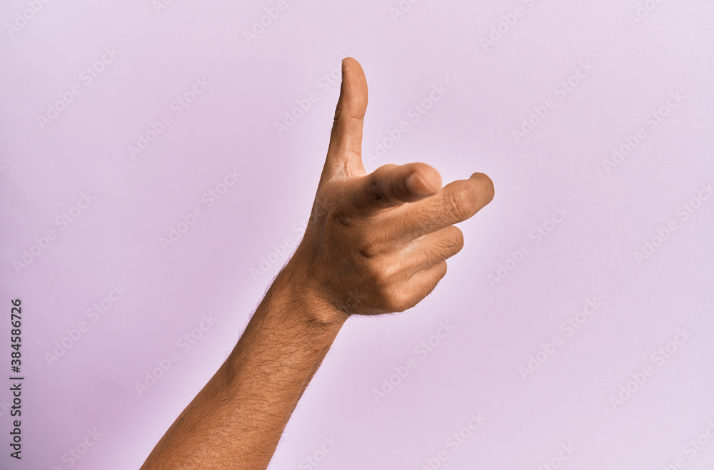 Arm and hand of caucasian young man over pink isolated background pointing forefinger to the camera, choosing and indicating towards direction