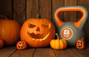 Heavy kettlebell with Halloween pumpkins on wooden background. Healthy fitness lifestyle autumn composition.