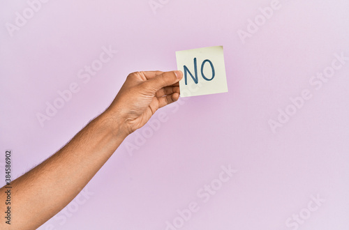 Hand of hispanic man holding no reminder paper over isolated pink background.
