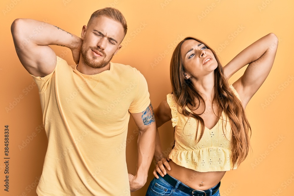 Young couple of girlfriend and boyfriend hugging and standing together suffering of neck ache injury, touching neck with hand, muscular pain Young couple of girlfriend and boyfriend hugging and standing together suffering of neck ache injury, touching neck with hand, muscular pain