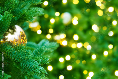 Festive New Year background, Christmas fir tree garlands, balls and toys. Christmas tree with holiday golden decorations and lights. Space for text. Illumination