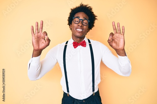 Handsome african american man with afro hair wearing hipster elegant look relax and smiling with eyes closed doing meditation gesture with fingers. yoga concept.