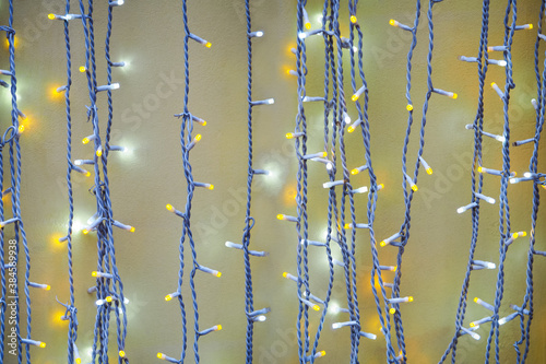 Light bulb decor. Garlands of burning light against the wall, yellow and white bulbs at night. New Year or christmas greeting card concept