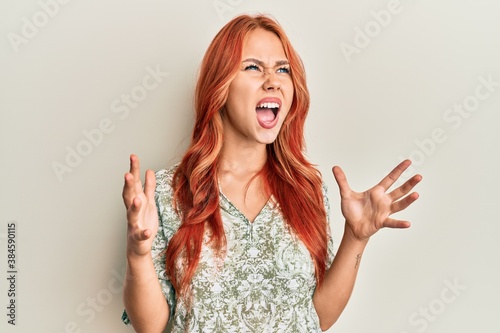 Young beautiful redhead woman wearing casual clothes crazy and mad shouting and yelling with aggressive expression and arms raised. frustration concept.