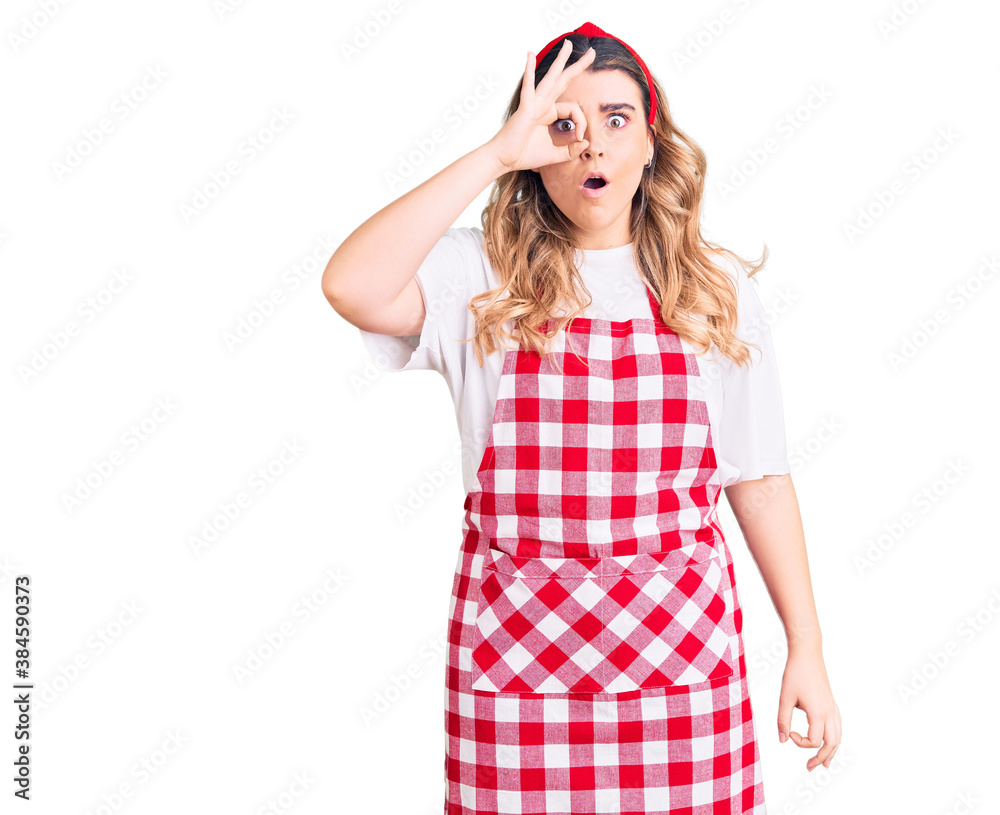 Young caucasian woman wearing apron doing ok gesture shocked with surprised face, eye looking through fingers. unbelieving expression. Young caucasian woman wearing apron doing ok gesture shocked with surprised face, eye looking through fingers. unbelieving expression.