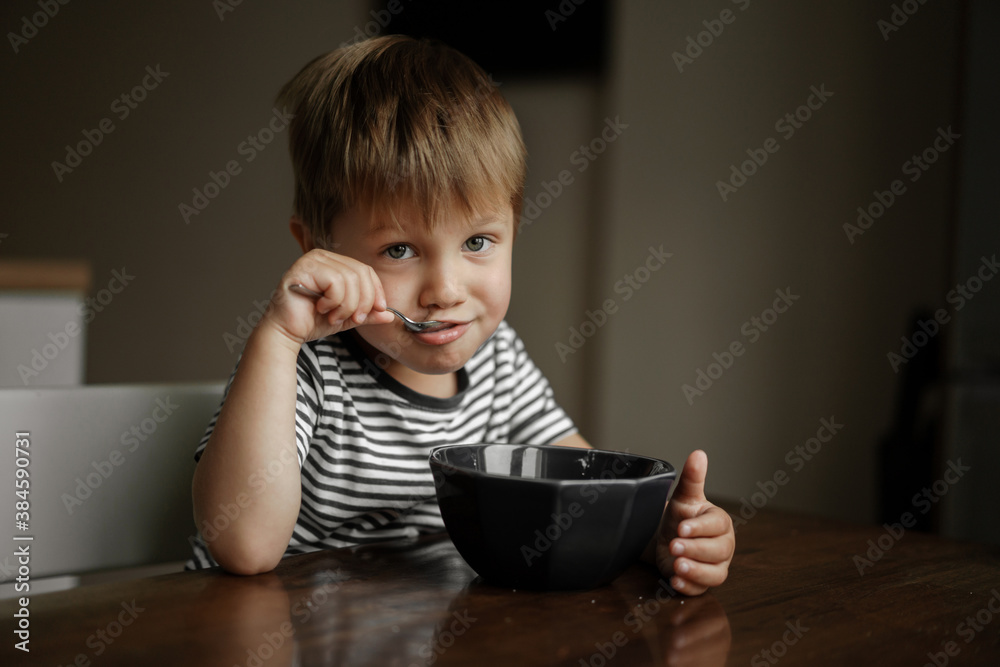 cute little boy eating oatmeals for beakfast. image with selective focus cute little boy eating oatmeals for beakfast. image with selective focus