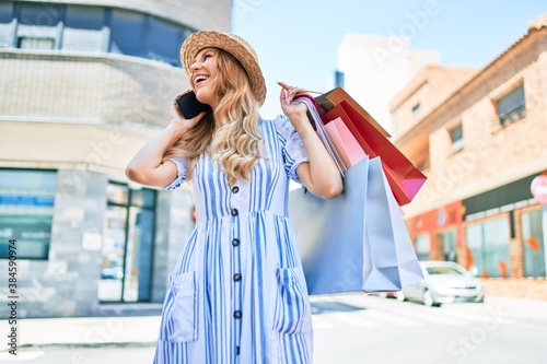 Young beautiful shopper woman smiling happy going to the shops sales holding shopping bags ourtdoors, smiling happy using smartphone © Krakenimages.com