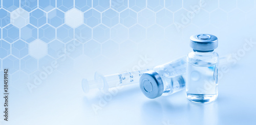 Medical syringe with a needle and a bollte with vaccine.