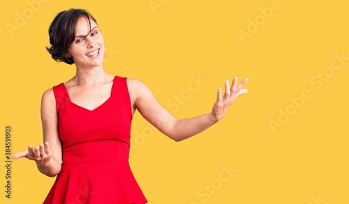 Beautiful young woman with short hair wearing casual style with sleeveless shirt smiling cheerful offering hands giving assistance and acceptance.