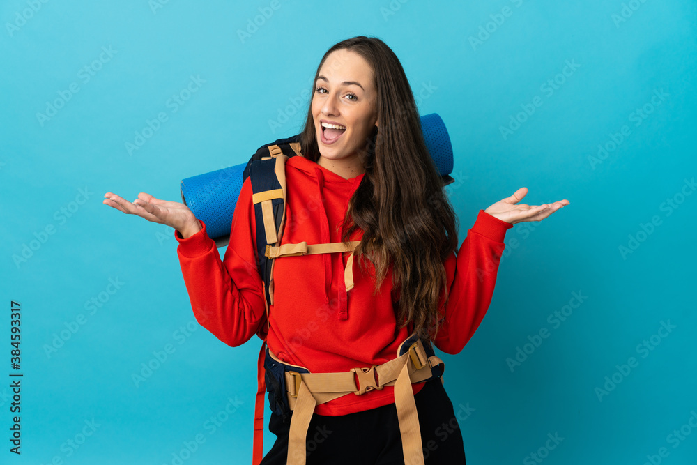 Mountaineer woman with a big backpack over isolated background with shocked facial expression Mountaineer woman with a big backpack over isolated background with shocked facial expression