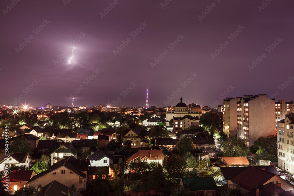 Night illuminated city during thunderstorms and lightning