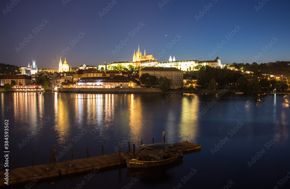 Pargue charles bridge and prague castle by night reflections river with boat motive in the front