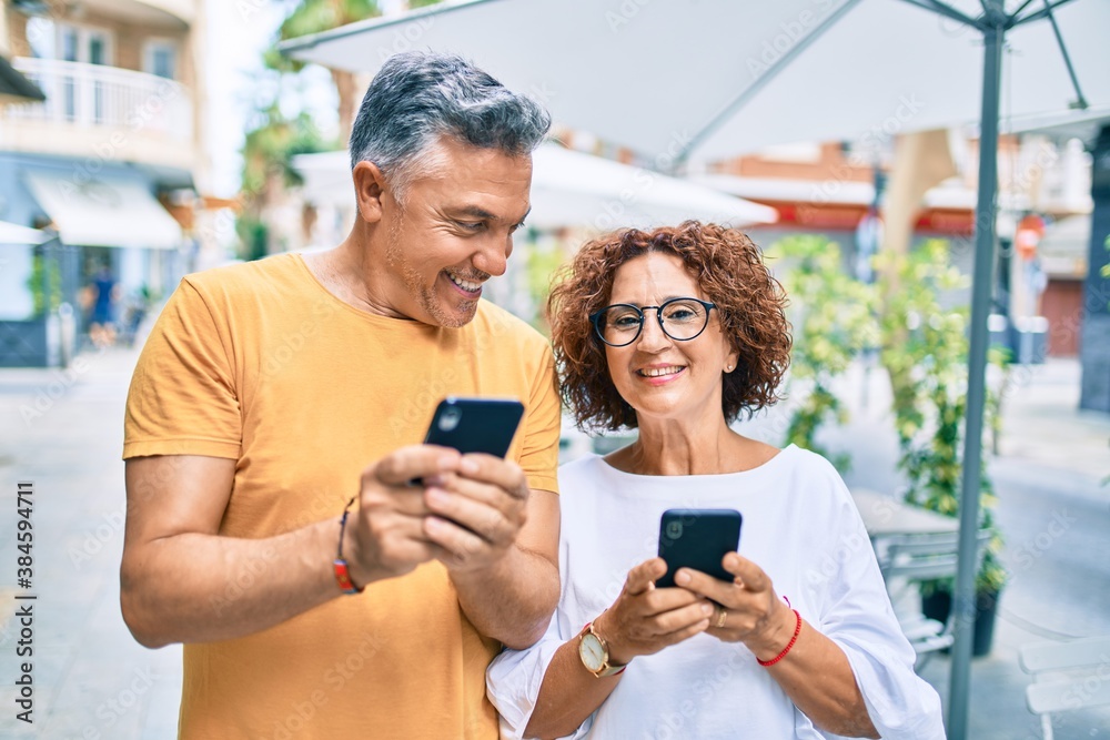 Middle age couple smiling happy using smartphone at street of city. Middle age couple smiling happy using smartphone at street of city.