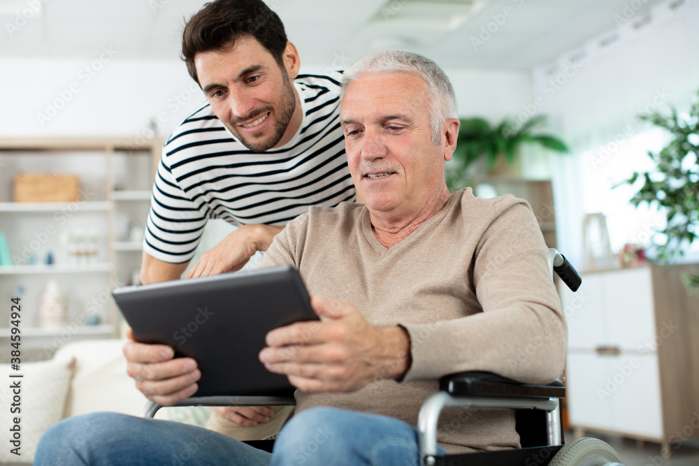 Fototapeta premium handsome man taking care about his eldery father in wheelchair