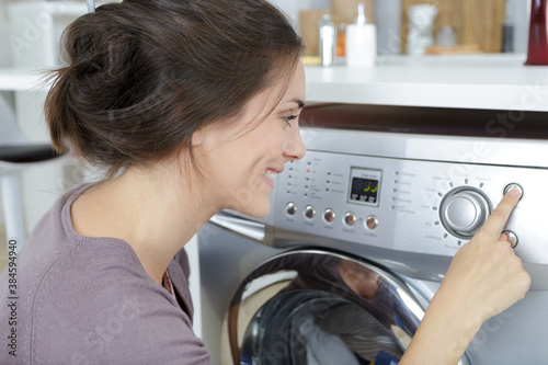 happy woman using washing machine in utility room