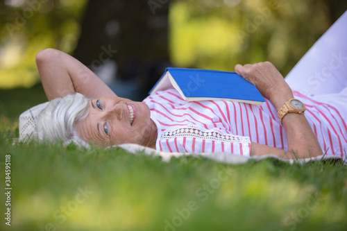 Fotografie senior woman reading book laid on the grass