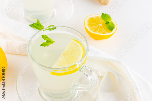 Ginger tea with lemon and mint on a white napkin. Two cups of ginger tea, lemon, ginger root and honey on white background. Top view