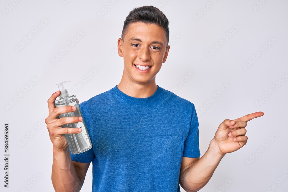 Young hispanic boy using hand sanitizer gel smiling happy pointing with hand and finger to the side Young hispanic boy using hand sanitizer gel smiling happy pointing with hand and finger to the side
