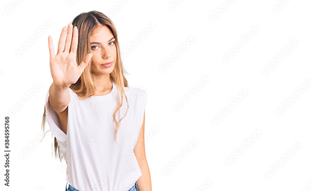 Beautiful caucasian woman with blonde hair wearing casual white tshirt doing stop sing with palm of the hand. warning expression with negative and serious gesture on the face. Beautiful caucasian woman with blonde hair wearing casual white tshirt doing stop sing with palm of the hand. warning expression with negative and serious gesture on the face.