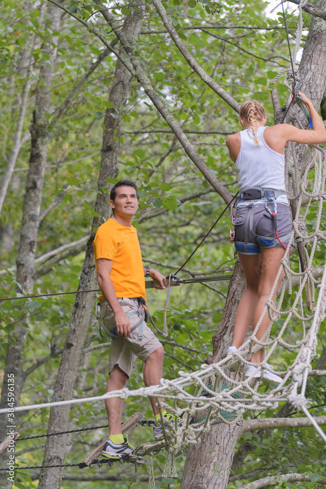 adults climbing rope bridge in the trees