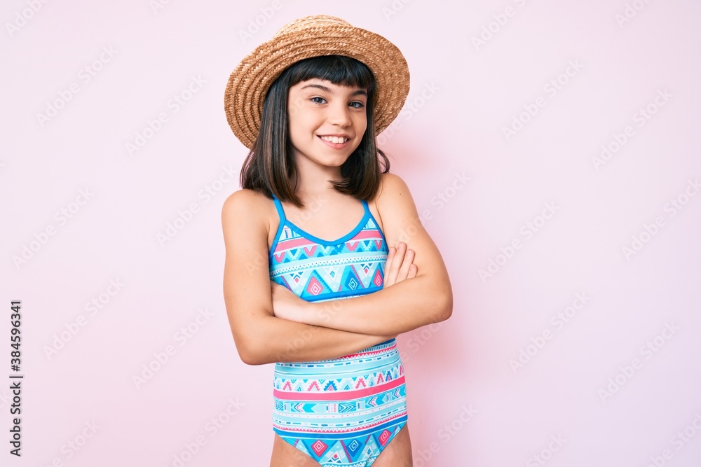 Young little girl with bang wearing swimsuit and summer hat happy face smiling with crossed arms looking at the camera. positive person. Young little girl with bang wearing swimsuit and summer hat happy face smiling with crossed arms looking at the camera. positive person.