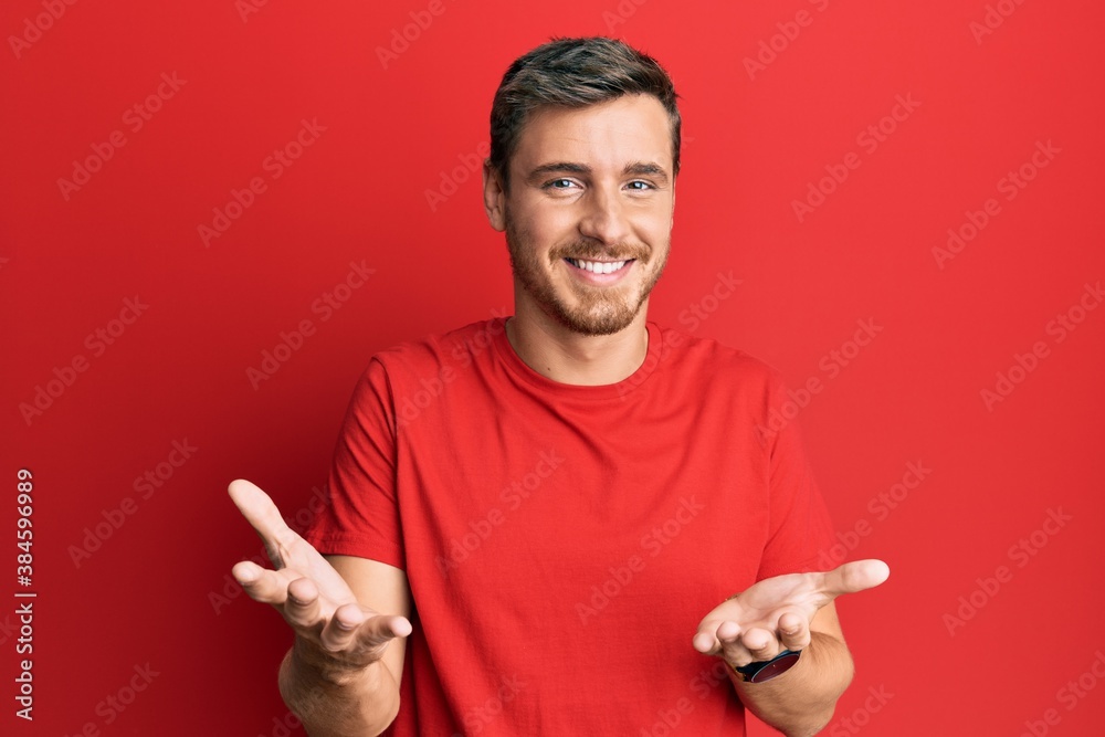 Handsome caucasian man wearing casual red tshirt smiling cheerful with open arms as friendly welcome, positive and confident greetings Handsome caucasian man wearing casual red tshirt smiling cheerful with open arms as friendly welcome, positive and confident greetings