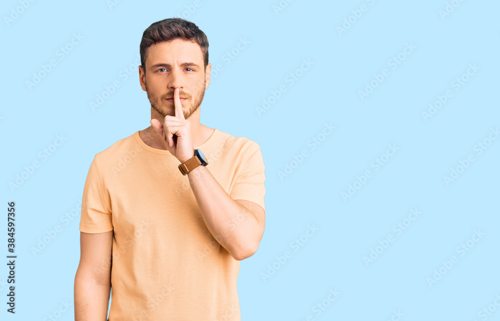 Handsome young man with bear wearing casual yellow tshirt asking to be quiet with finger on lips. silence and secret concept. Handsome young man with bear wearing casual yellow tshirt asking to be quiet with finger on lips. silence and secret concept.