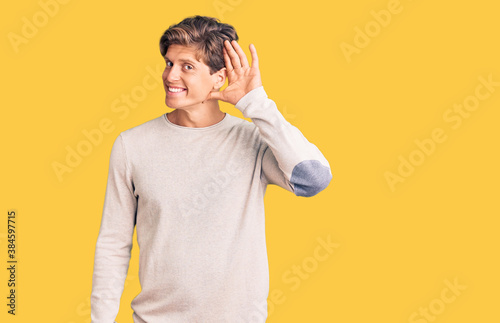 Young handsome man wearing casual clothes smiling with hand over ear listening an hearing to rumor or gossip. deafness concept.