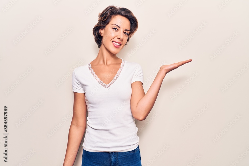 Young beautiful woman wearing casual clothes smiling cheerful presenting and pointing with palm of hand looking at the camera. Young beautiful woman wearing casual clothes smiling cheerful presenting and pointing with palm of hand looking at the camera.