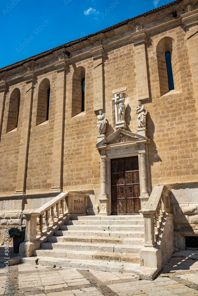 Gravina in Puglia, Italy. The side of the cathedral. The staircase leading to the church entrance. The wooden portal adorned with columns and marble statues.