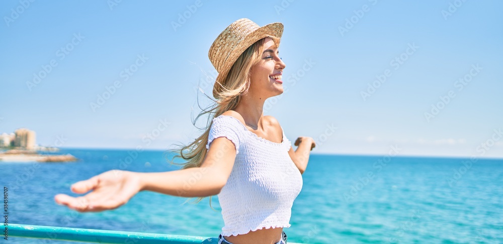 Young blonde tourist girl breathing with close eyes and open arms at the promenade. Young blonde tourist girl breathing with close eyes and open arms at the promenade.