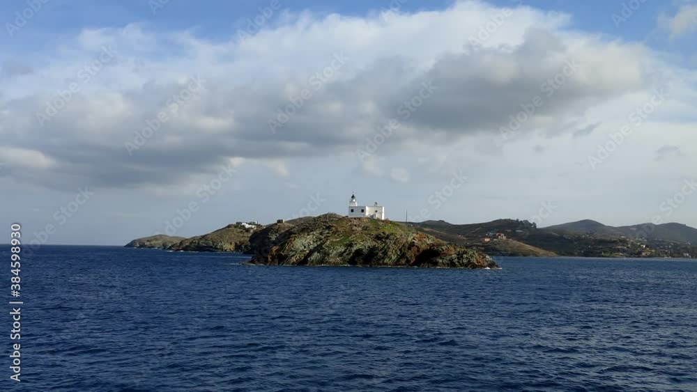 Greece, Kea Tzia island. Seascape with lighthouse, clear blue sky, view from a moving ship. Greece, Kea Tzia island. Seascape with lighthouse, clear blue sky, view from a moving ship.