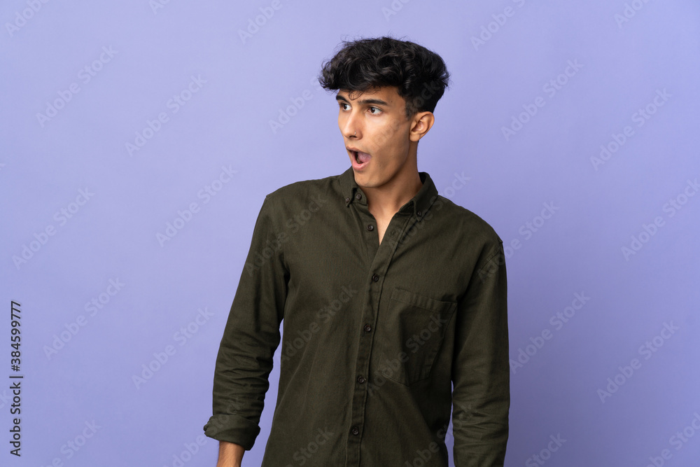 Obraz premium Young Argentinian man isolated on background doing surprise gesture while looking to the side