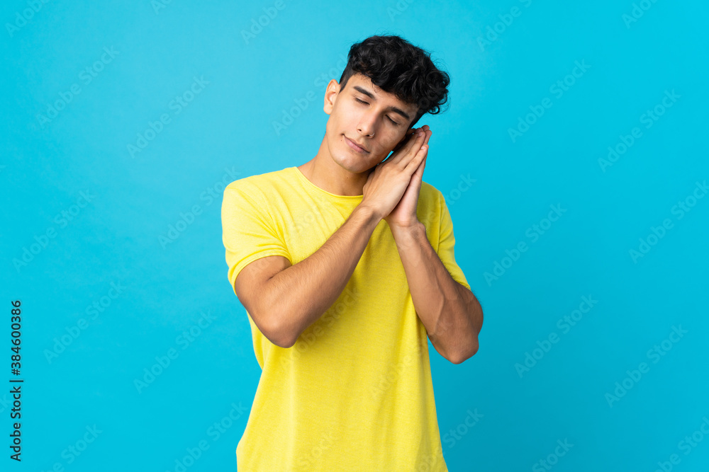Young Argentinian man isolated on background making sleep gesture in dorable expression Young Argentinian man isolated on background making sleep gesture in dorable expression